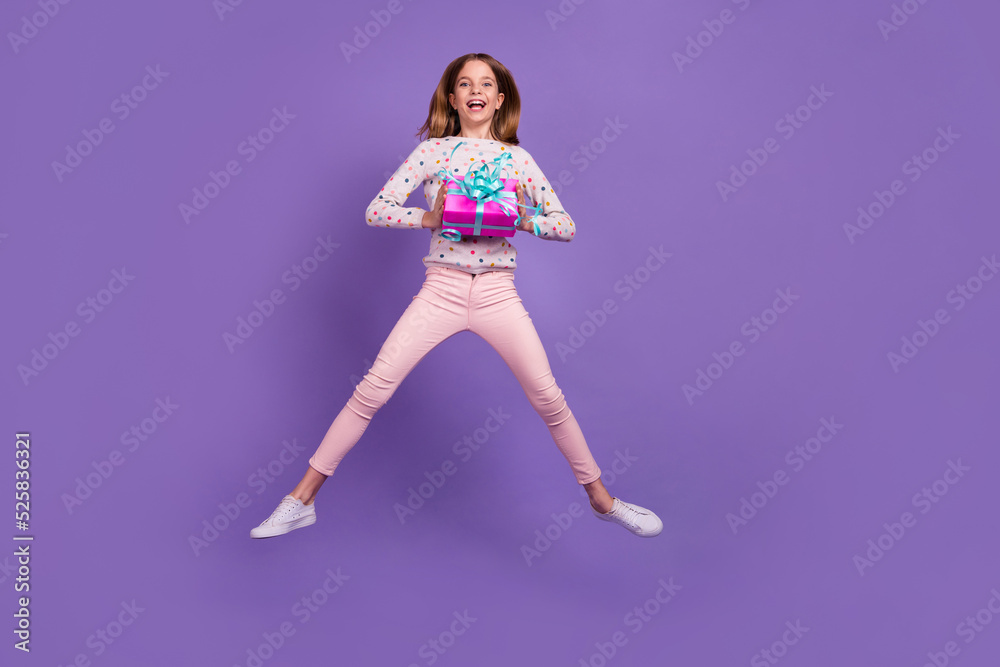 Full body portrait of carefree charming girl jumping hands hold giftbox isolated on purple color background Full body portrait of carefree charming girl jumping hands hold giftbox isolated on purple color background