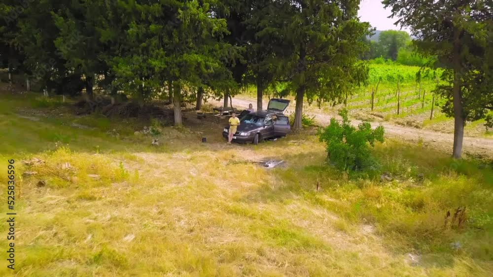 Aerial Drone panorama of vineyards and agricultural fields in Kakheti in Georgia. View of drone from car with two people travelers, drone flies away and shows valley with mountains.