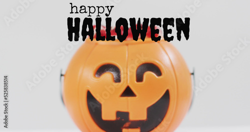 Neon trick or treat text banner against pumpkin shaped bucket full of halloween candies