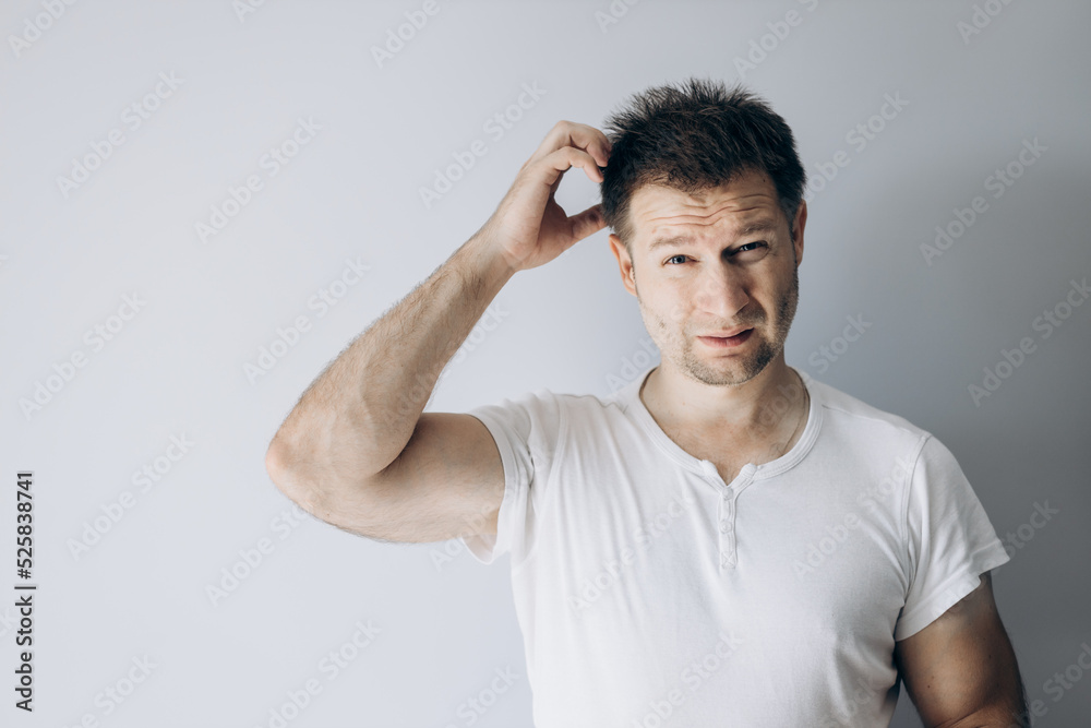 Guy programmer in a white t-shirt holds thinking Guy programmer in a white t-shirt holds thinking