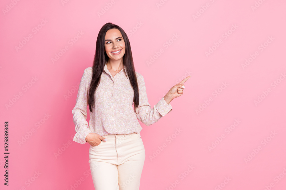Photo of young gorgeous pretty woman hold hand pocket finger pointing looking empty space ad isolated on pink color background Photo of young gorgeous pretty woman hold hand pocket finger pointing looking empty space ad isolated on pink color background