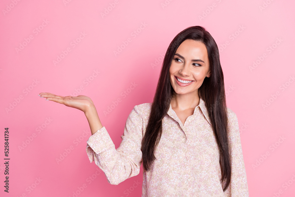 Photo of young attractive cute smiling woman interested looking hold hand product promoter isolated on pink color background Photo of young attractive cute smiling woman interested looking hold hand product promoter isolated on pink color background