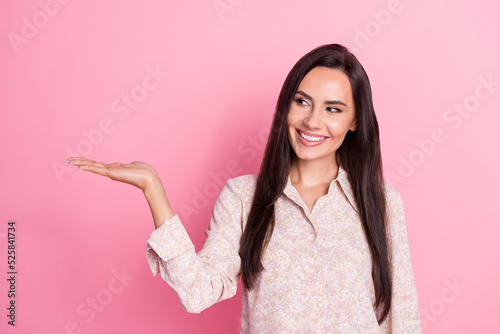 Photo of young attractive cute smiling woman interested looking hold hand product promoter isolated on pink color background © deagreez