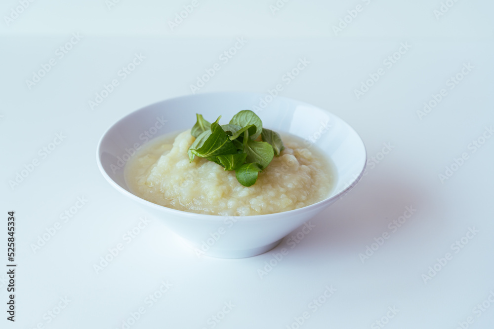Healthy vegan cauliflower cream soup with herbs in white bowl Healthy vegan cauliflower cream soup with herbs in white bowl