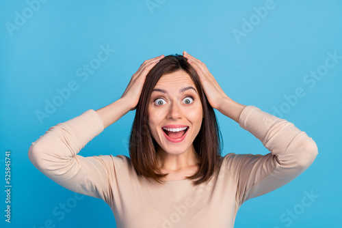 Photo of impressed cheerful girl arms touch head open mouth cant believe isolated on blue color background
