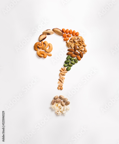 Stylized question mark made of cashew nuts, peanuts, brazil nuts, walnuts, almonds, popcorn and pistachio, isolated on white