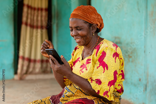 elderly african woman holding her smartphone rejoices