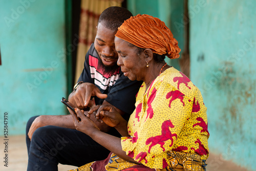 young african man assisting an elderly woman using her phone