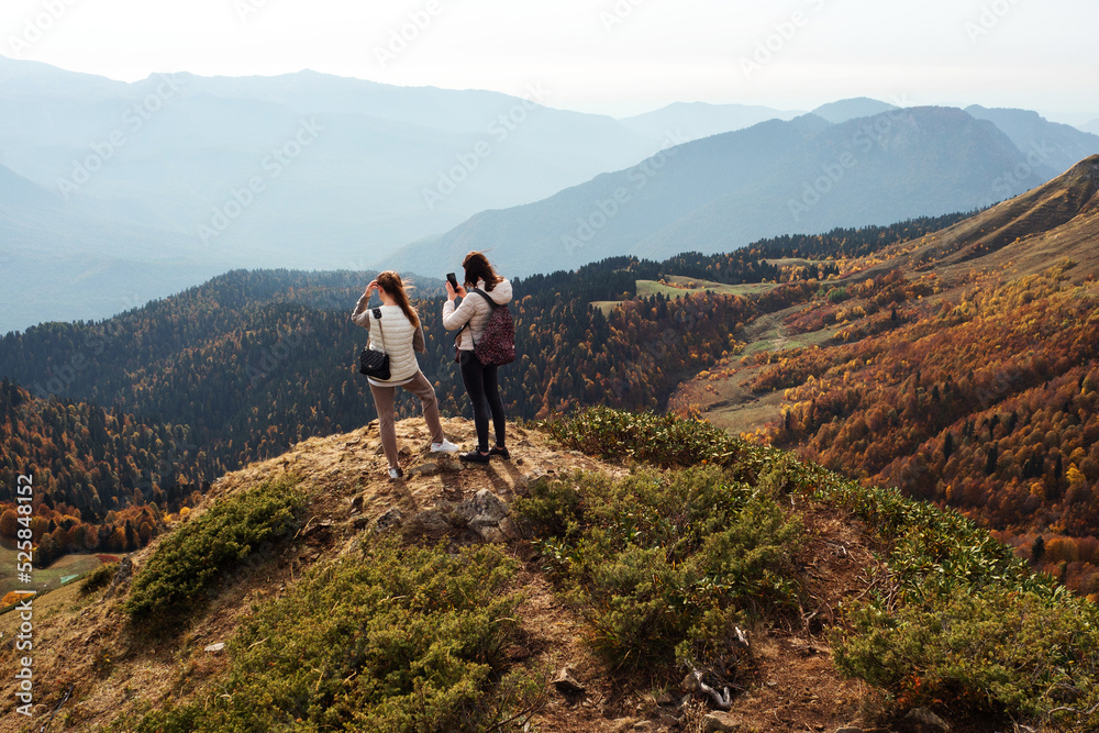 Two friends of a traveler on the top of a mountain look at a beautiful panorama, beautiful nature, the Caucasus mountains in Russia