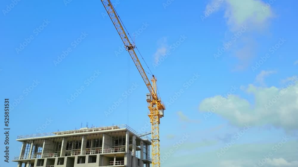 Drone flight of construction crane on construction site with constructed building. Against background of blue sky and clouds. Housing construction, apartment block. Real estate and developer. Business Drone flight of construction crane on construction site with constructed building. Against background of blue sky and clouds. Housing construction, apartment block. Real estate and developer. Business
