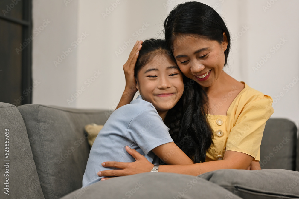 Affectionate loving middle aged mother cuddling grownup child, Excited to see daughter, happy mom cuddling her daughter, sitting together on comfortable sofa in living room. Affectionate loving middle aged mother cuddling grownup child, Excited to see daughter, happy mom cuddling her daughter, sitting together on comfortable sofa in living room.