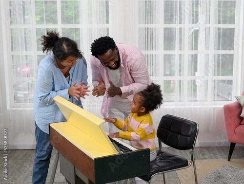 Little girl play on a piano with parent in the living room © brostock