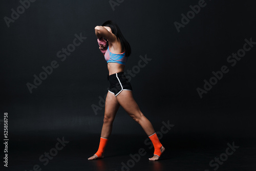 Sportsman muay thai woman boxer posing in training studio