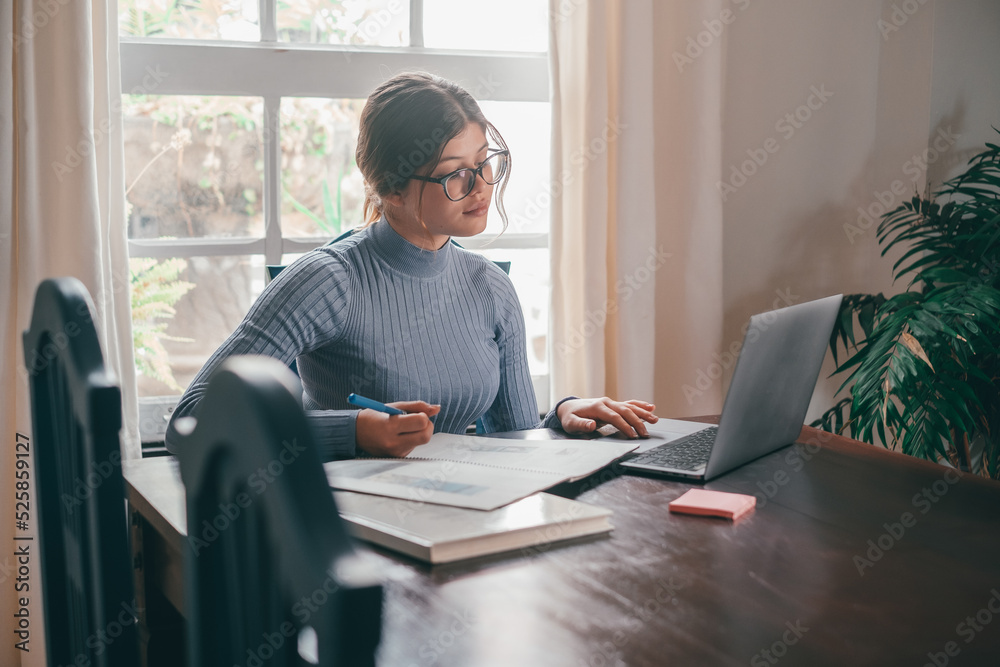 One young pretty woman studying and doing homework at home on the table. Female teenager using laptop or computer surfing the net indoor. One young pretty woman studying and doing homework at home on the table. Female teenager using laptop or computer surfing the net indoor.