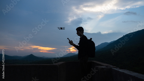 Silhouette of a aerial photographer or traveller flying drone in the nature during the blue hour
