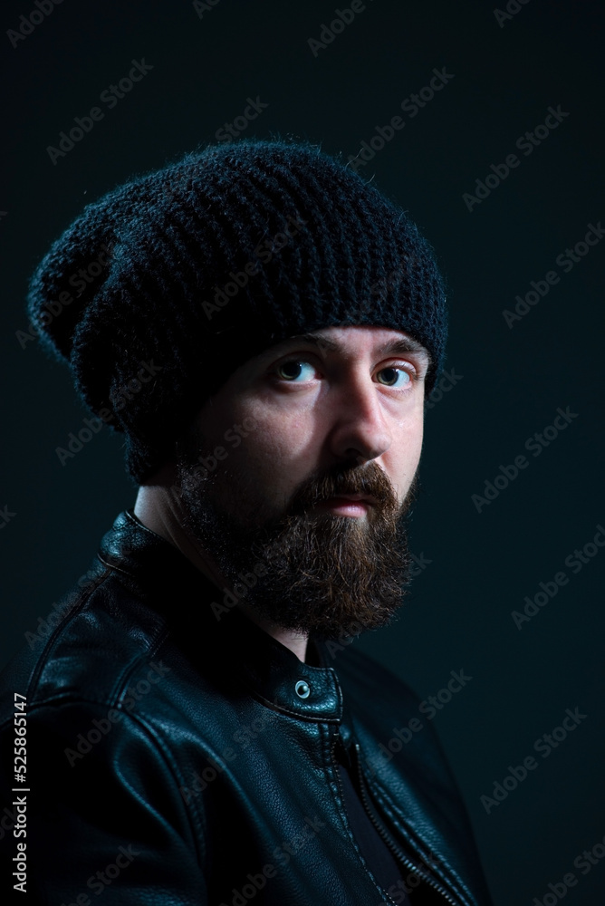 dramatic portrait of bearded millennial guy in leather jacket on dark background dramatic portrait of bearded millennial guy in leather jacket on dark background
