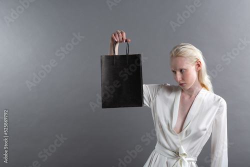 White caucasian albino blond woman holds shopping bag. Sale and discounts on market and Black Friday concept.