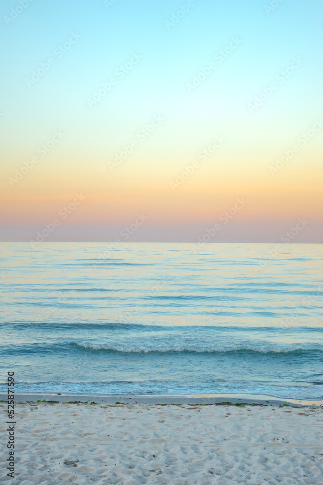 Serene and tranquil background of waves at the beach with a tropical yellow orange and gold sunset by the sea