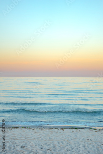 Serene and tranquil background of waves at the beach with a tropical yellow orange and gold sunset by the sea