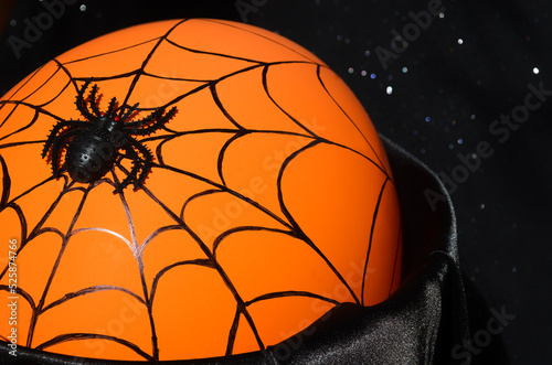 Halloween decor - black spider and cobwebs on a solid orange background.