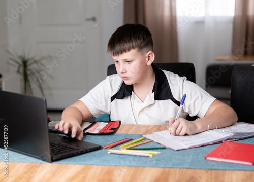 Caucasian boy using his computer while doing homework.