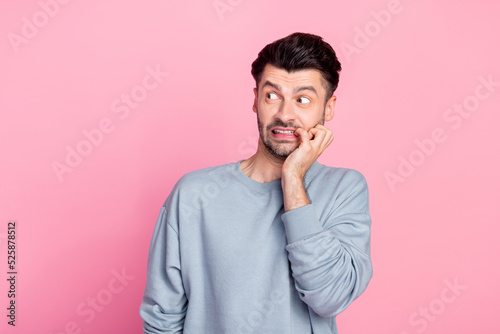 Photo of nervous anxious person biting finger nail look empty space isolated on pink color background