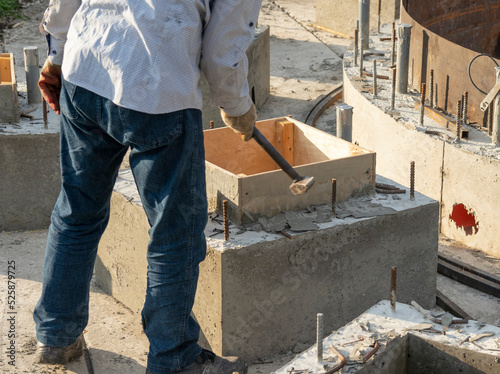 A worker removes wooden formwork after the concrete structure hardens at a construction site.