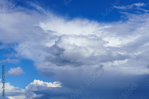 Fluffy white cloud in clear blue sky on sunny day in front of dark low storm cloud