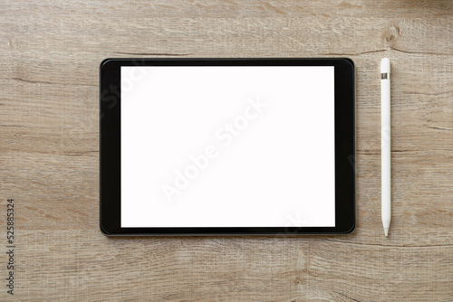 Black tablet with white blank screen is on top of brown paper with supplies. Top view, flat lay.