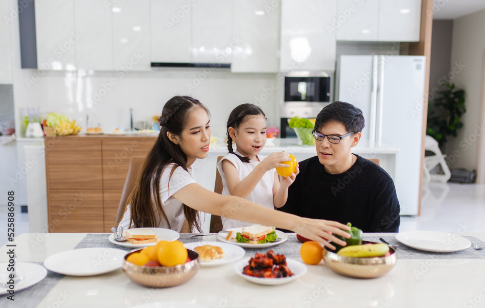 Asian family having meals together and showing thumbs up at home happily, Happy young parents are having fun with their little daughter during lunch at the dining table.
