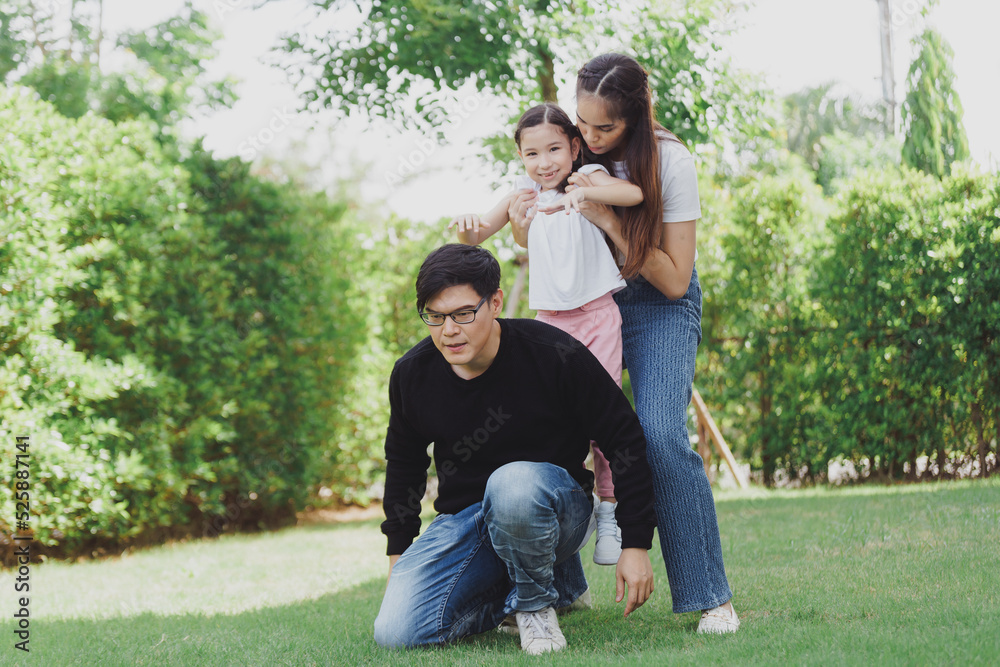 Portrait of a happy Asian family consisting of parents and children happy together for the holidays. Asian Family with a child playing on a lawn,  enjoyment relaxing recreational concept.