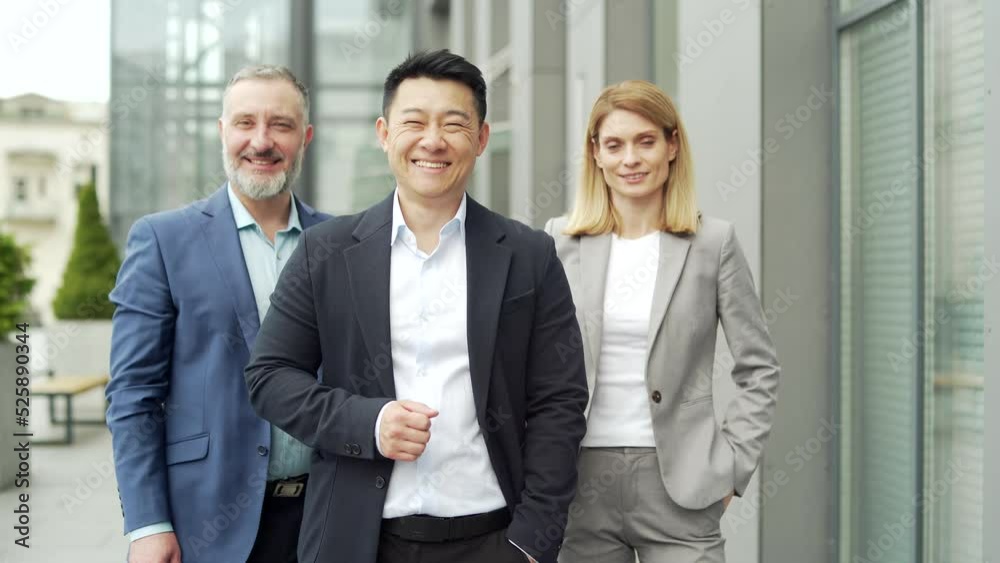 portrait of multiracial happy professional team of business people, businessmen employees in formal suits looking at camera. Group office workers outside Asian man, Caucasian woman and mature male portrait of multiracial happy professional team of business people, businessmen employees in formal suits looking at camera. Group office workers outside Asian man, Caucasian woman and mature male
