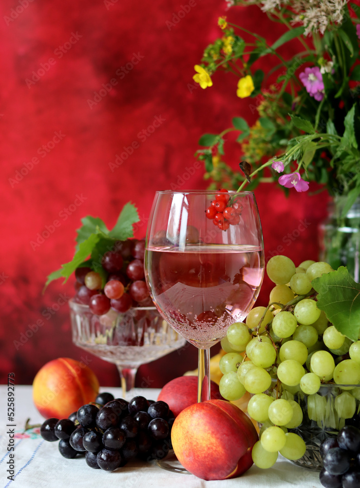 Glass of pink wine, grapes, berries and flowers on a table. Delicious summer food close up photo. Textured background with copy space. Glass of pink wine, grapes, berries and flowers on a table. Delicious summer food close up photo. Textured background with copy space.