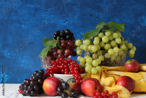 Colorful still life with seasonal berries on a table. Red currant  green grapes  nectarines and apples close up photo. Nutrition concept. 