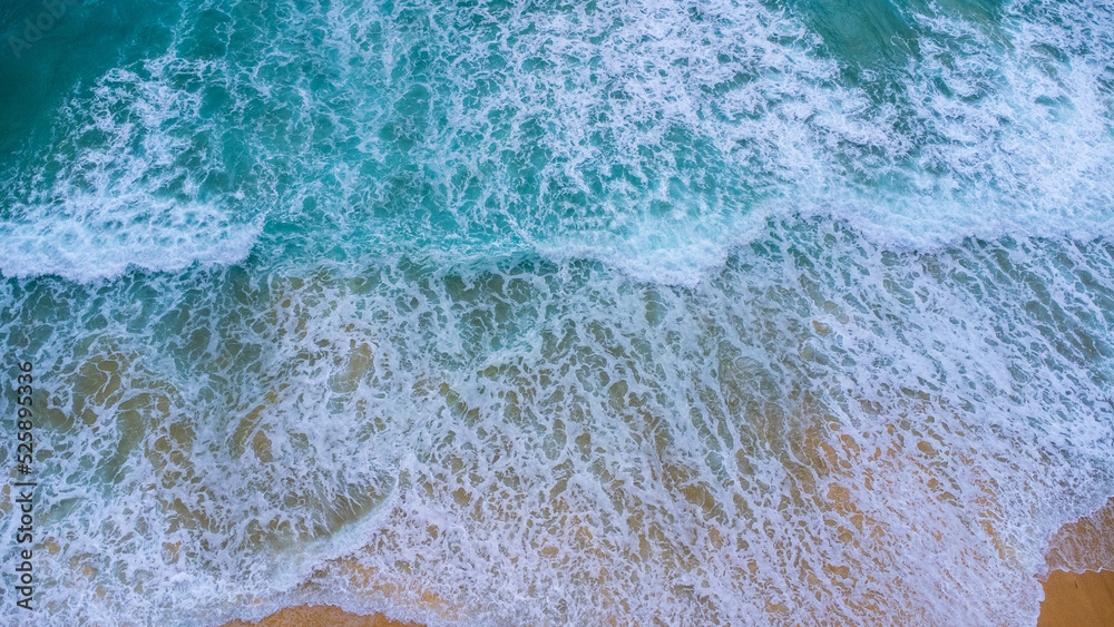 Fototapeta premium Beautiful sea waves and white sand beach in the tropical island. Soft waves of blue ocean on sandy beach background from top view from drones. Concept of relaxation and travel on vacation.