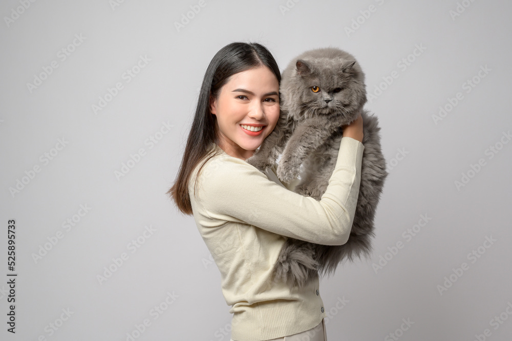 A young woman is holding lovely cat , playing with cat in studio on white background