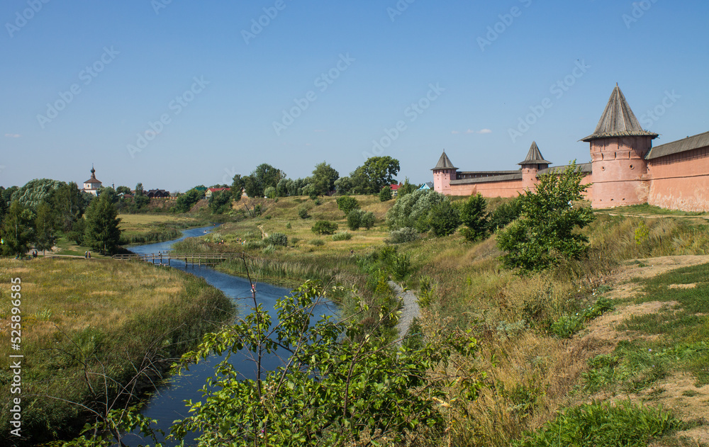 Brick walls of the ancient Kremlin in Suzdal russia on a high hill among green trees and grass on a bright sunny summer day and a space for copying