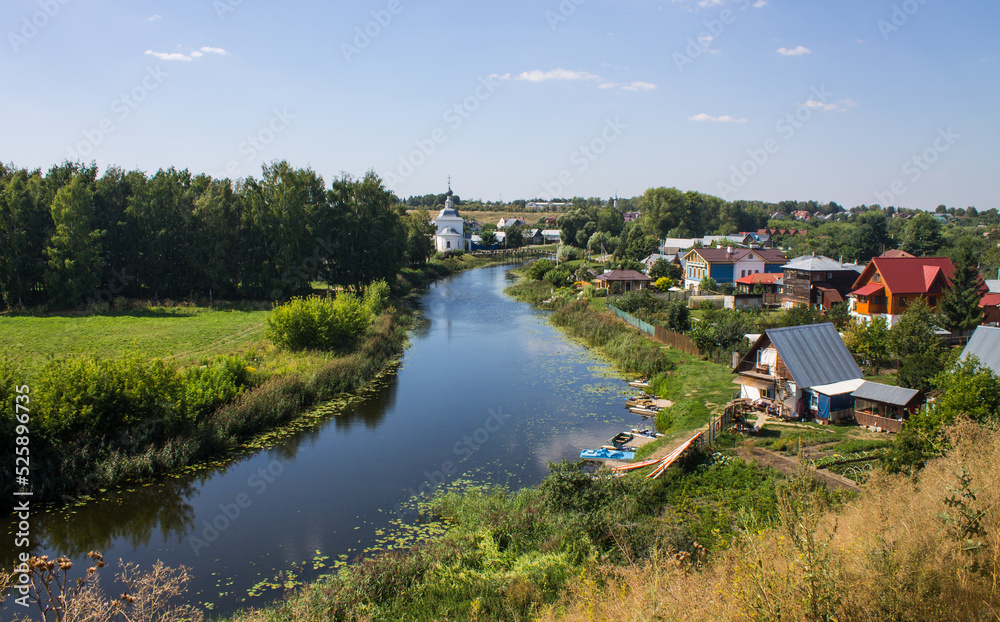 Panoramic top view of the city of Suzdal in Russia with historical architecture and a church among the lush green foliage of trees and a small river on a sunny summer day Panoramic top view of the city of Suzdal in Russia with historical architecture and a church among the lush green foliage of trees and a small river on a sunny summer day