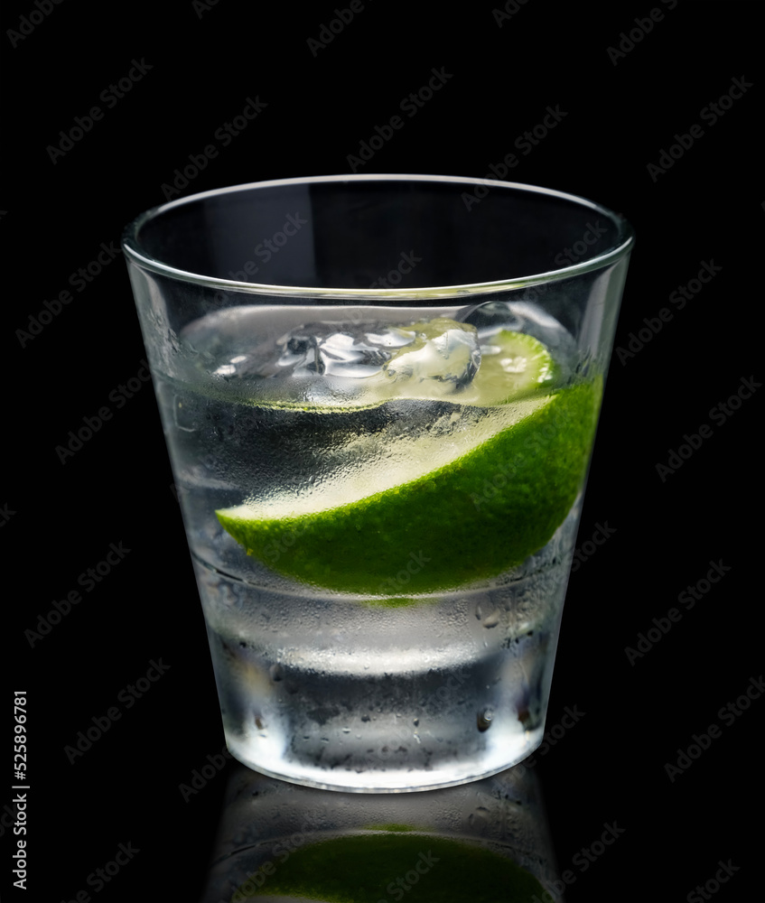 Vodka or gin with lime in rocks glass on grey background Vodka or gin with lime in rocks glass on grey background
