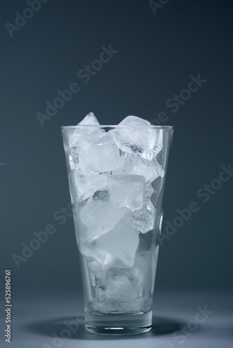 Glass tumbler with ice on a dark background, still life