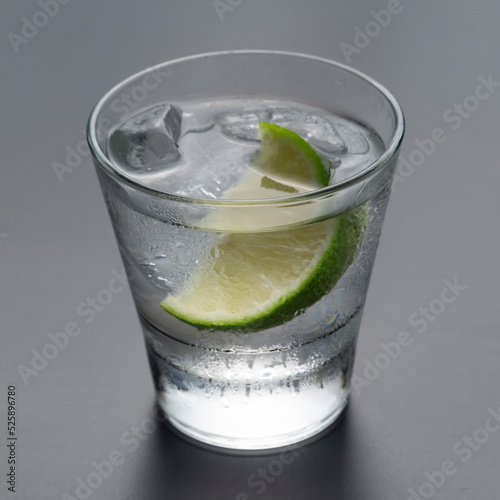 Vodka or gin with lime in rocks glass on grey background photo