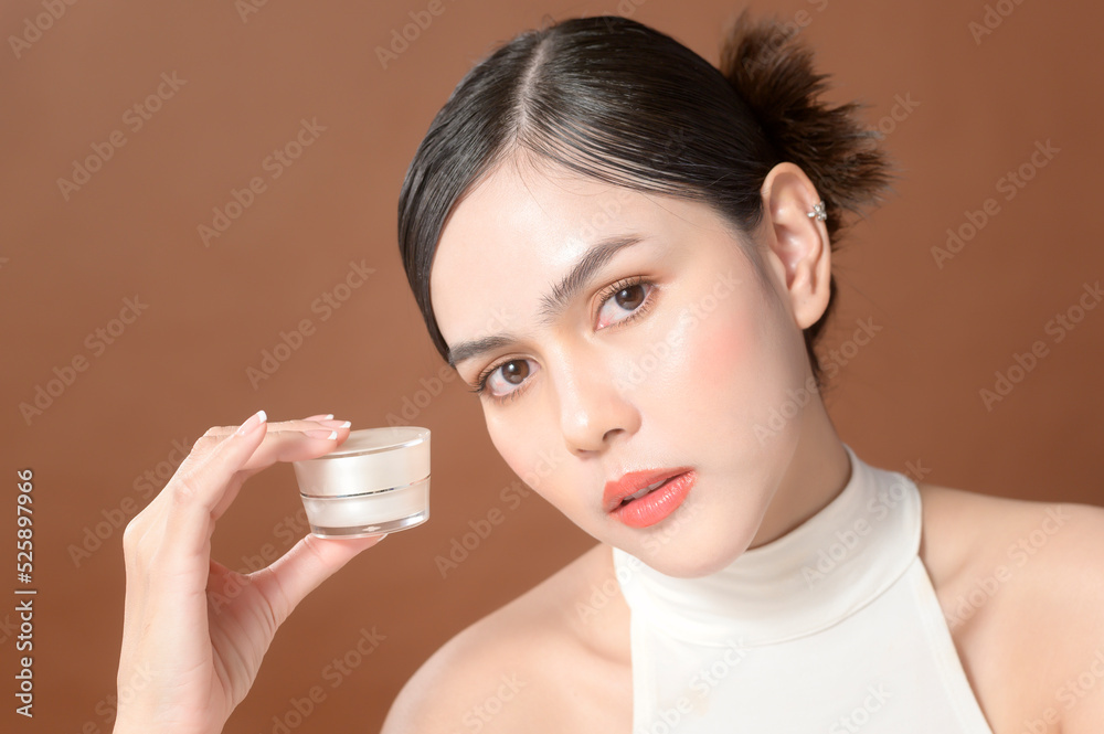 A young woman with beautiful face is holding cream , using cream of her face , beauty skin care concept