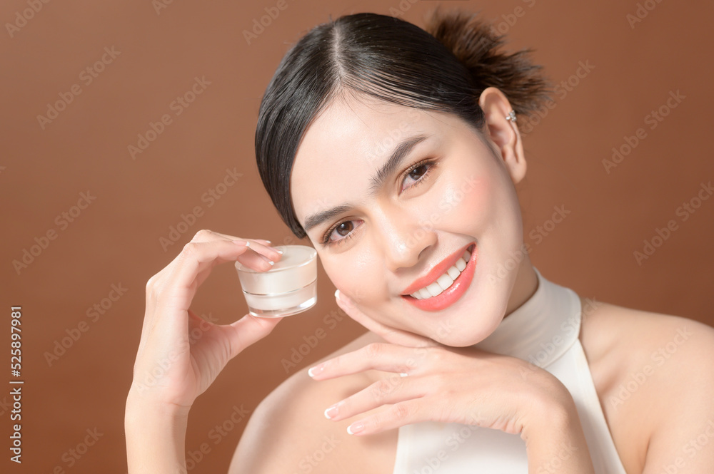A young woman with beautiful face is holding cream , using cream of her face , beauty skin care concept A young woman with beautiful face is holding cream , using cream of her face , beauty skin care concept