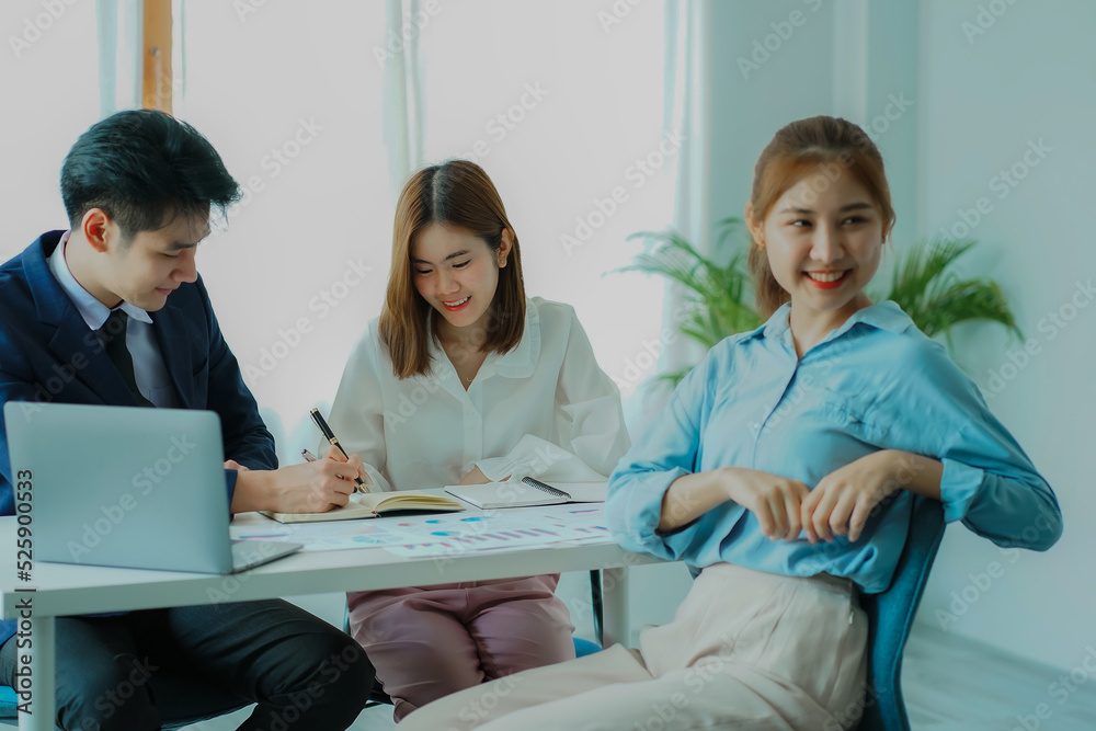 Successful Asian man, manager, businessman working with an Asian female colleague at a desk in a company office with a financial graph and laptop on the table. Successful Asian man, manager, businessman working with an Asian female colleague at a desk in a company office with a financial graph and laptop on the table.