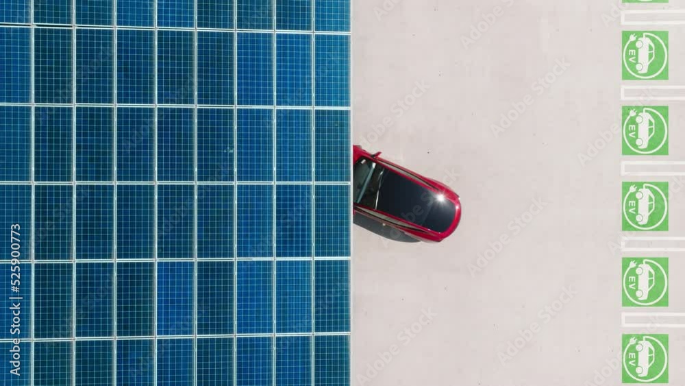 Innovative technology 4K aerial footage. Overhead view on modern red electric vehicle backing up. Charged car from the renewable natural source of sun energy generated in solar batteries, EV charging