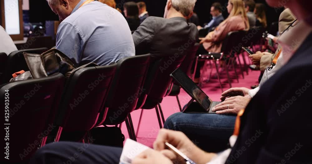 Close up of people seated in an auditorium listening to lecture and taking notes Close up of people seated in an auditorium listening to lecture and taking notes