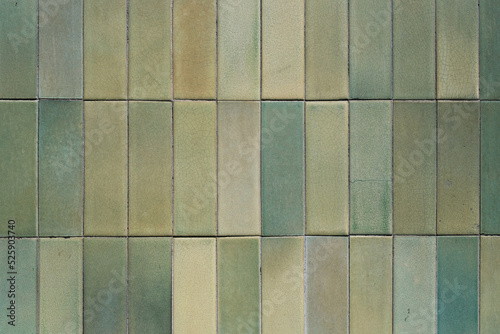 Texture and pattern of a green ceramic wall tiles, grunge square mosaic close up, background, retro facade of the building.