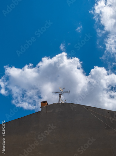 old television antenna and blue sky on concrete building roof