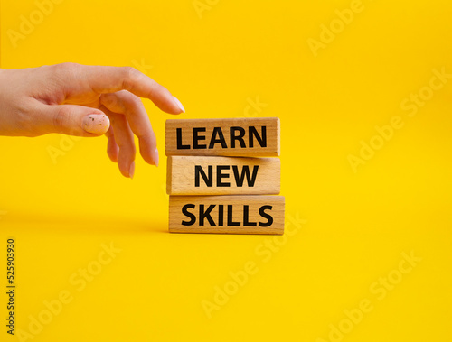 Learn new skills symbol. Concept words 'Learn new skills' on wooden blocks. Beautiful yellow background. Businessman hand. Business and Learn new skills concept. Copy space. photo