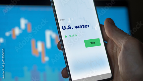 An investor's analyzing the U.S. water etf fund on screen. A phone shows the ETF's prices u.s. water to invest